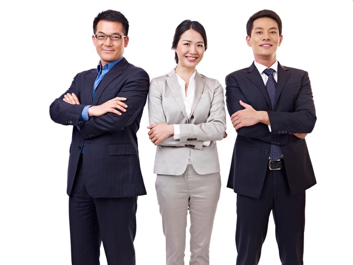 three people standing with arms folded and smiling